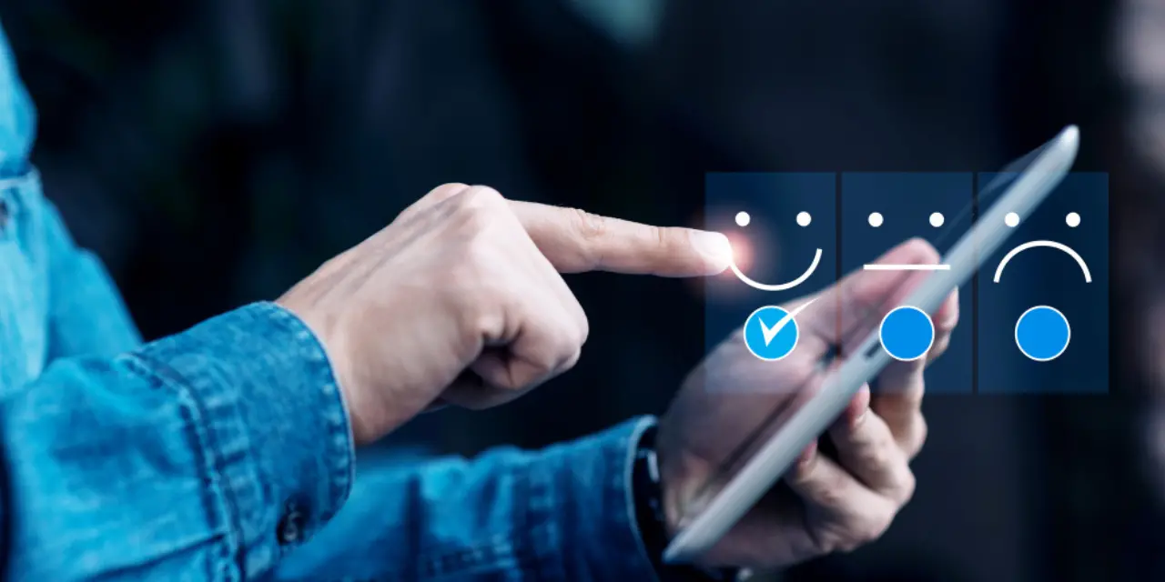 Person tapping a satisfaction rating icon on a tablet.