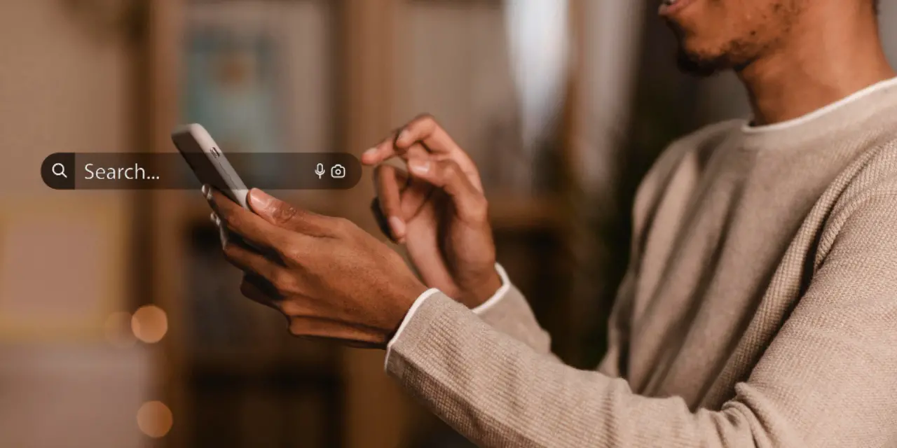 Person using a smartphone with a search interface on screen.