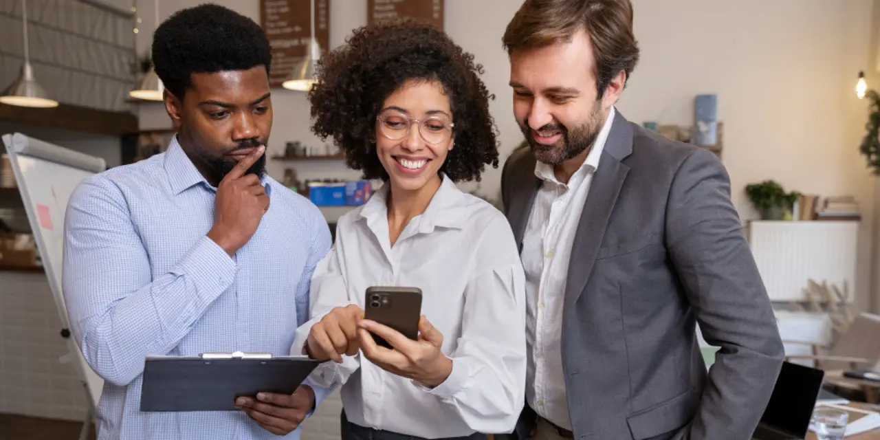 Group of professionals reviewing information on a smartphone at the workplace.