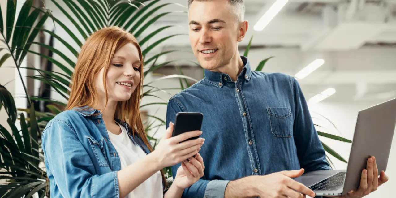 Young professionals sharing information on a smartphone in a modern office.