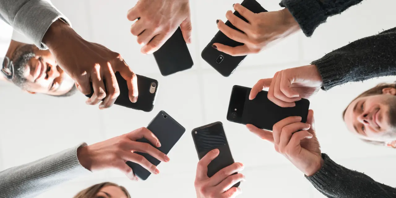 Group of people holding cell phones in a circle.