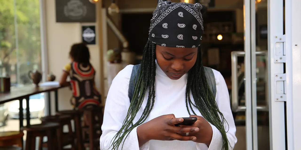 Menina com o celular na mão explorando as ferramentas do aplicativo da ClickCard