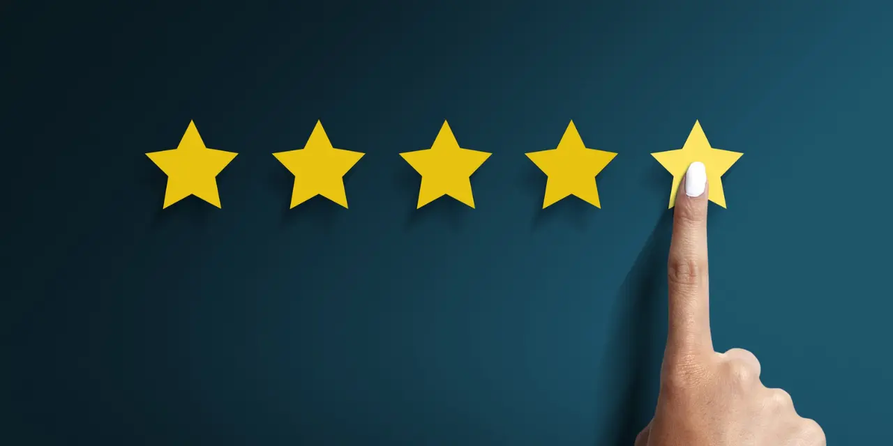 Hand touching the fifth star in a five-star review.