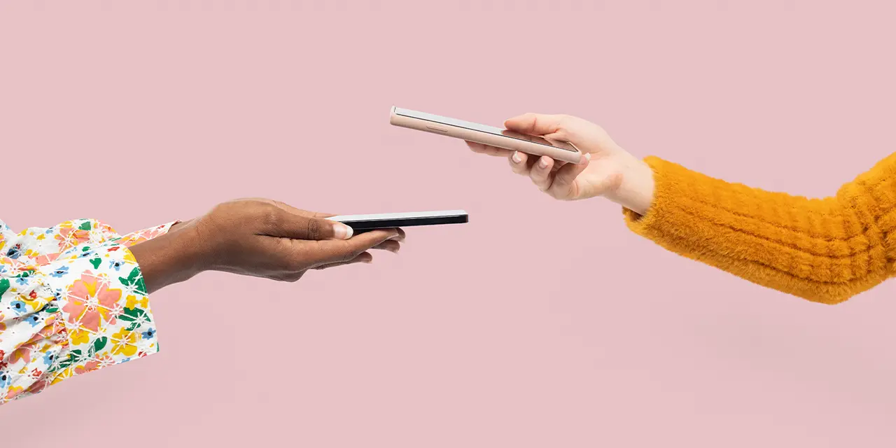 Duas pessoas trocando cartões de visita digitais por meio do recurso NFC de seus celulares.